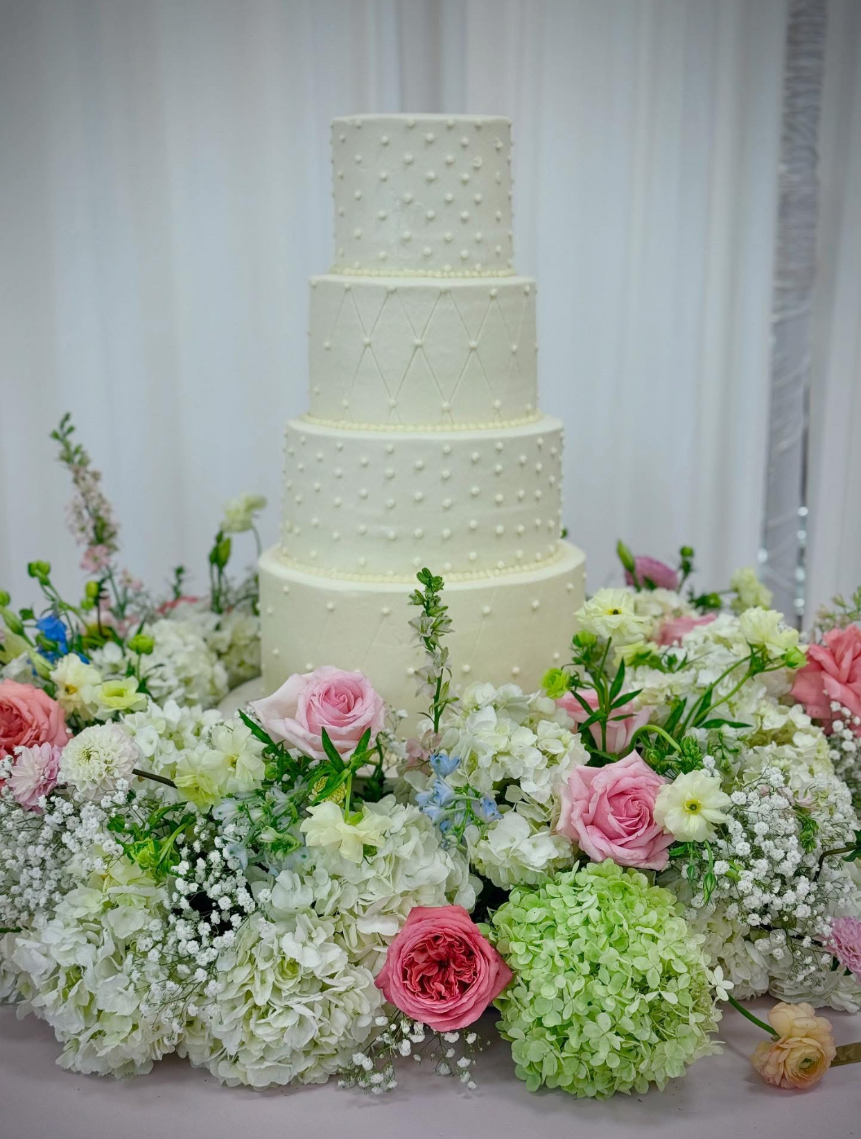 wedding cake surrounded by colorful flowers
